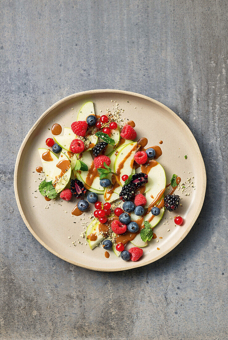 Süße Apfelscheiben mit Beeren, Mandelmus und Hanfsamen