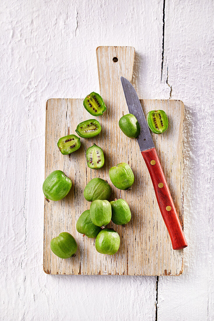 Kiwi berries, whole and halved, on wooden board