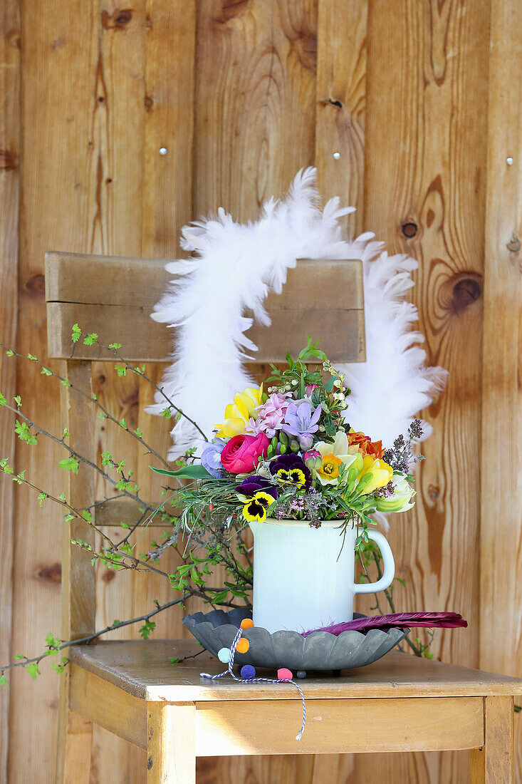 Colorful spring bouquet with feather wreath on wooden chair