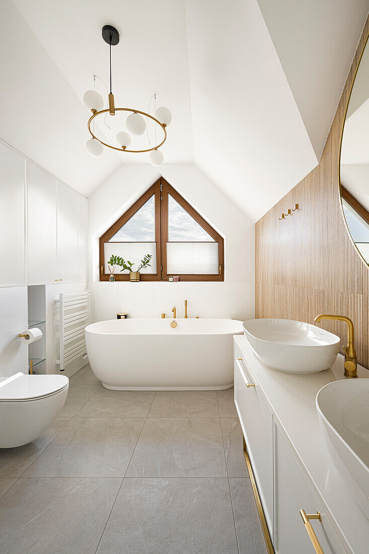 Waschtisch und freistehende Badewanne unter dem Fenster in weißem Badezimmer