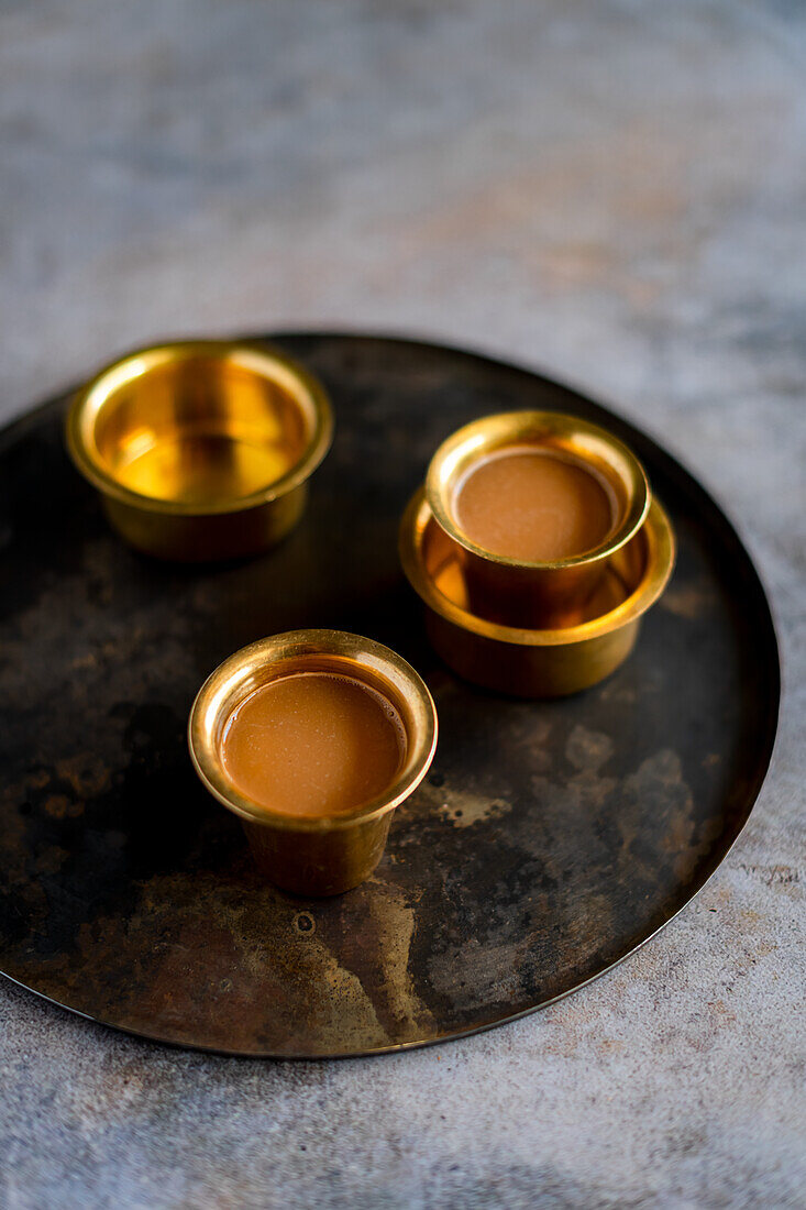 Masala Chai in goldenen Bechern auf Tablett