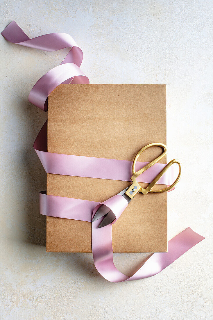 Geschenkkarton mit rosa Schleifenband und Schere
