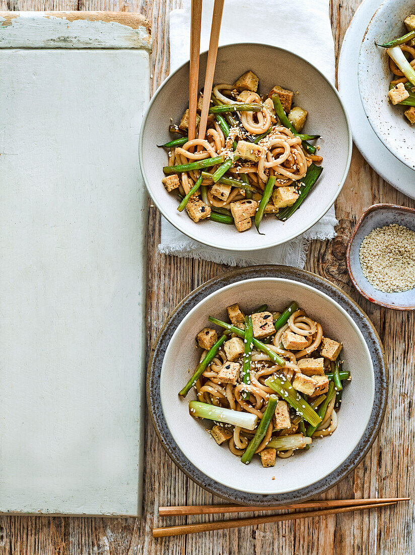Stir-fried udon noodles with sesame seeds, spring onions, and crispy tofu