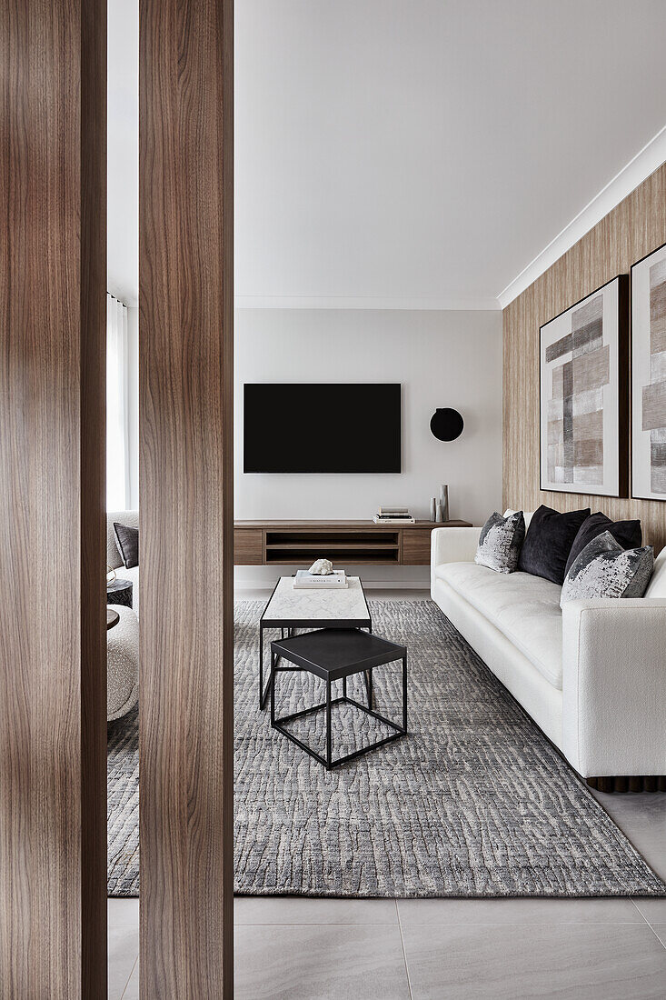 Entrance hall in neutral tones, looking into lounge area with cream sofas and stone and metal coffee tables