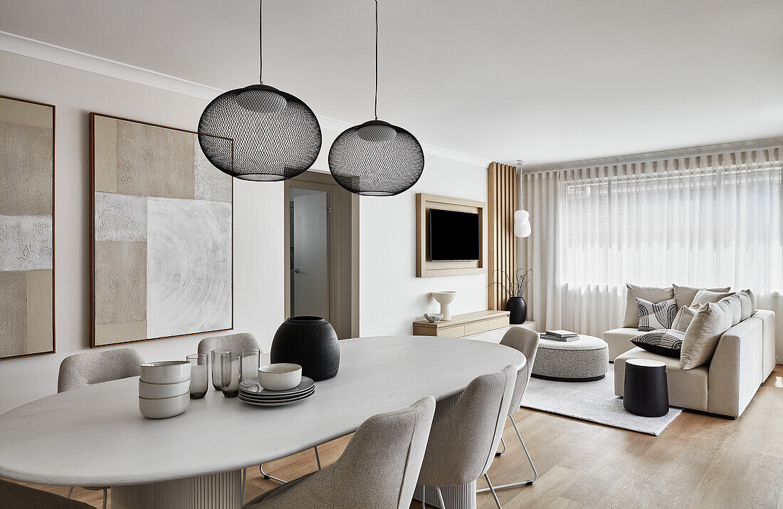 Coastal style open plan living area with white 80s style column dining table, upholstered chairs and cream sofa