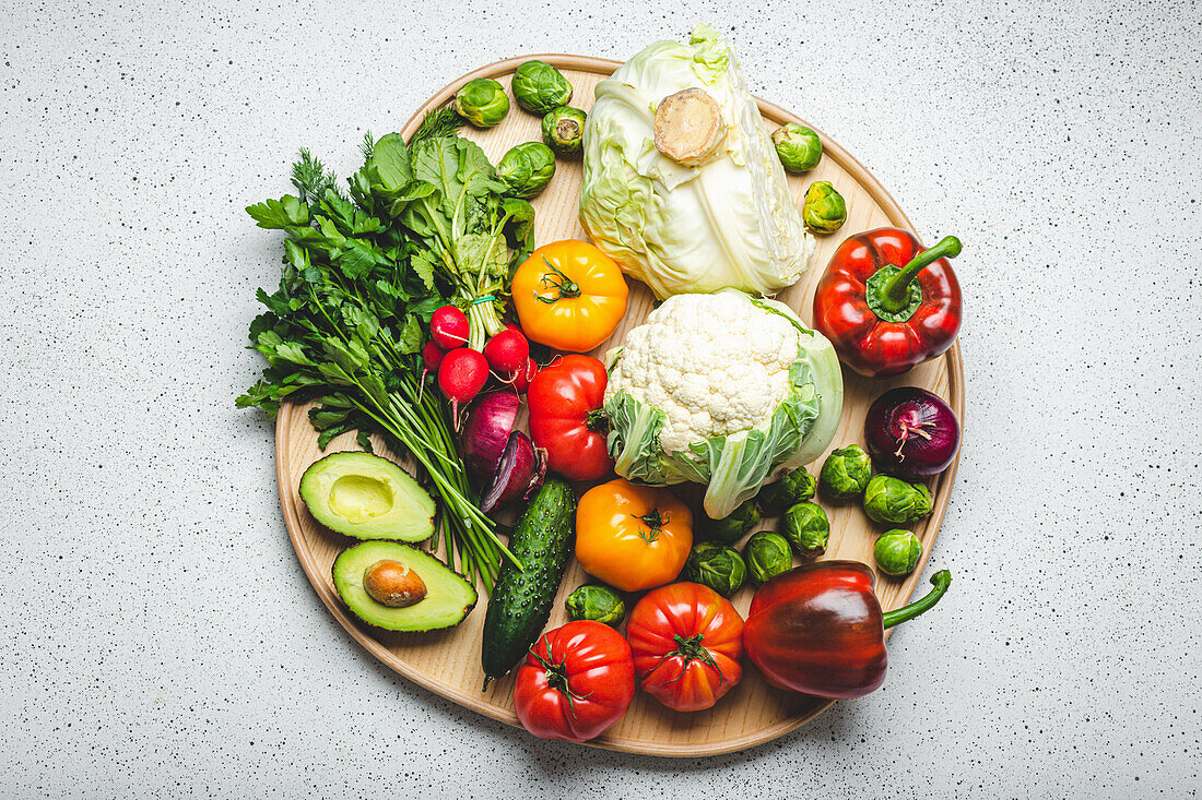 A wooden tray with fresh vegetables and herbs