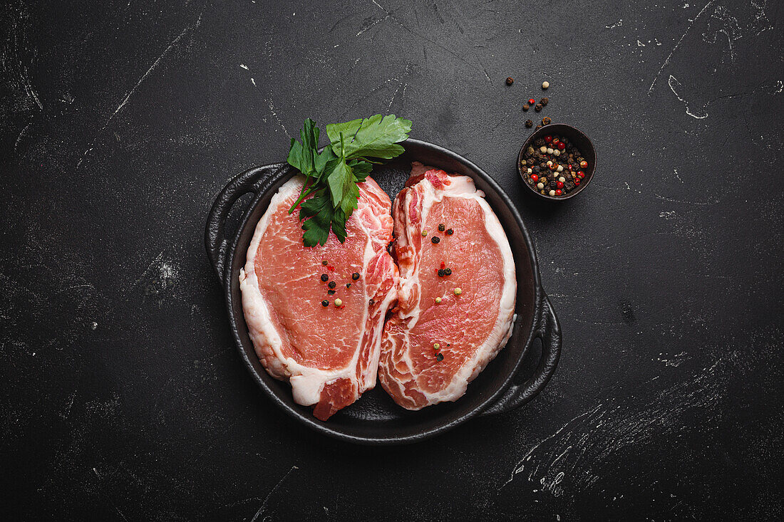 Raw pork steaks in a black cast iron pan