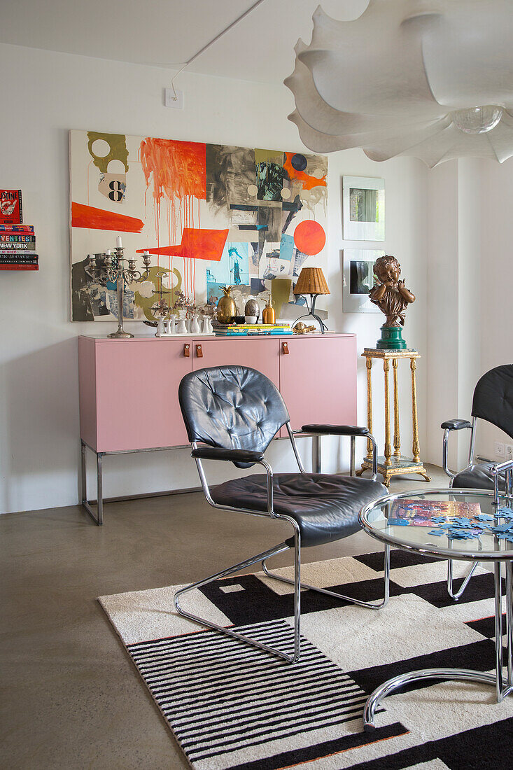 Living room with modern art, sideboard in pastel pink and ceiling light