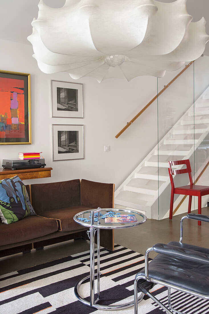 Bright living room with seating furniture, ceiling light, staircase in the background