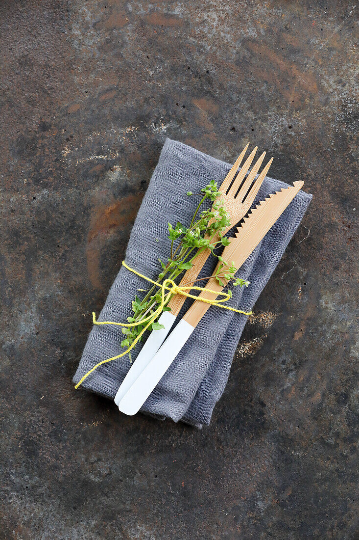 Wooden cutlery and cloth napkin wrapped with ribbon and chickweed twigs