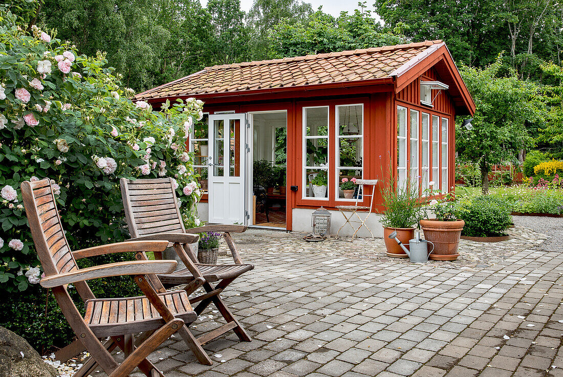 Orangery made from recycled window frames, with garden chairs in the foreground