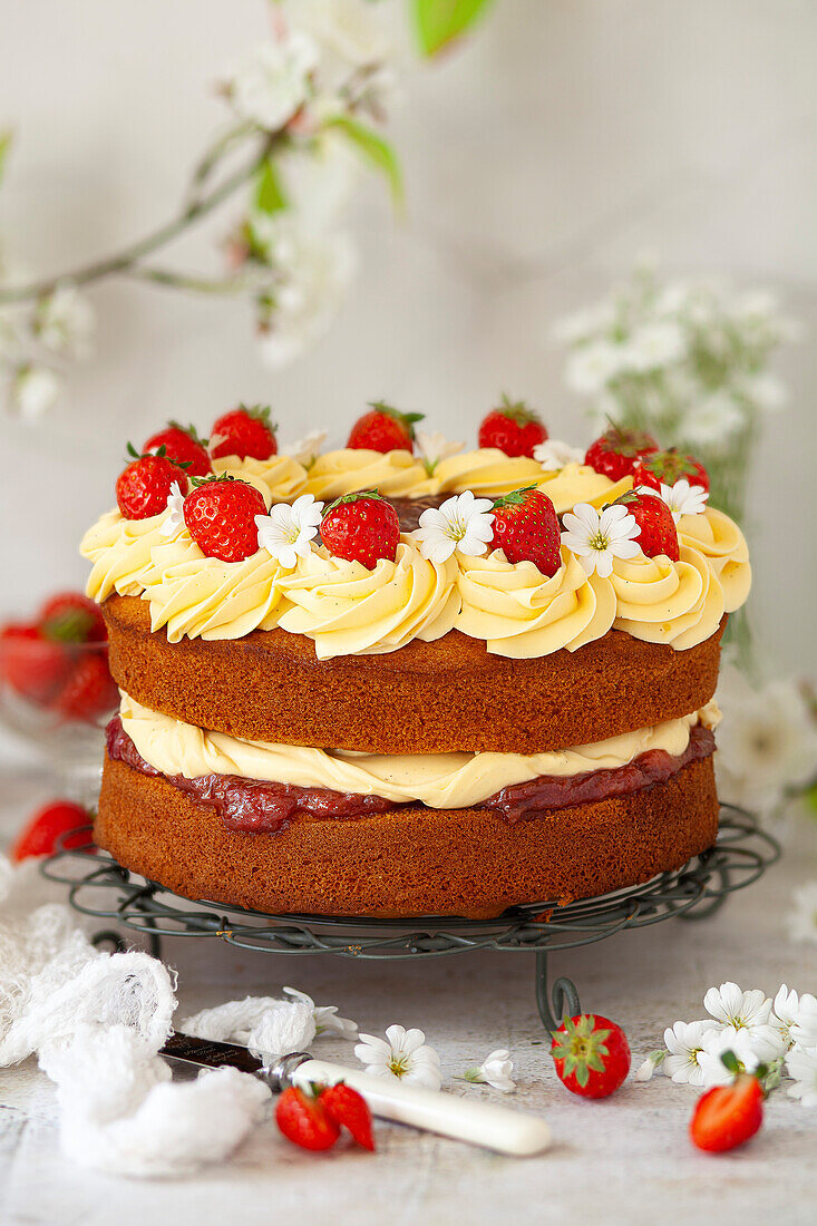 Cream cake with jam, strawberries and flowers