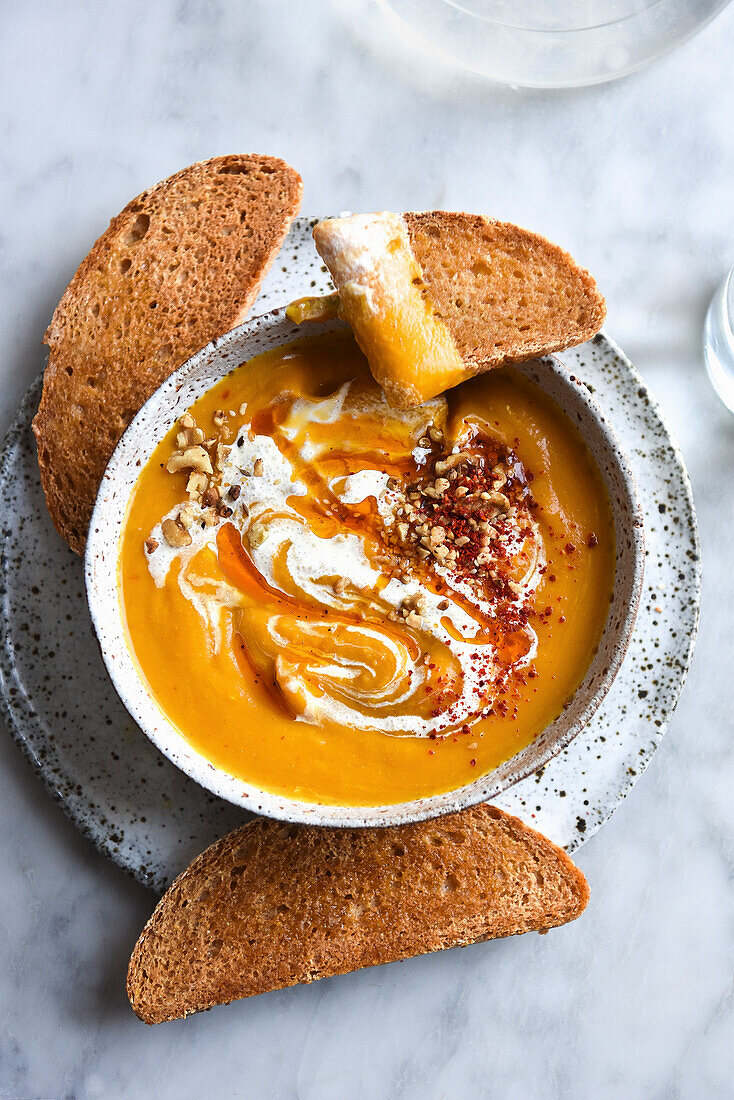 Kürbissuppe mit Joghurt, serviert mit Brot