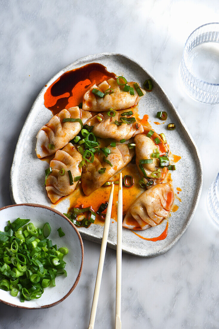 Steamed dumplings in chili oil, black rice vinegar and spring onions