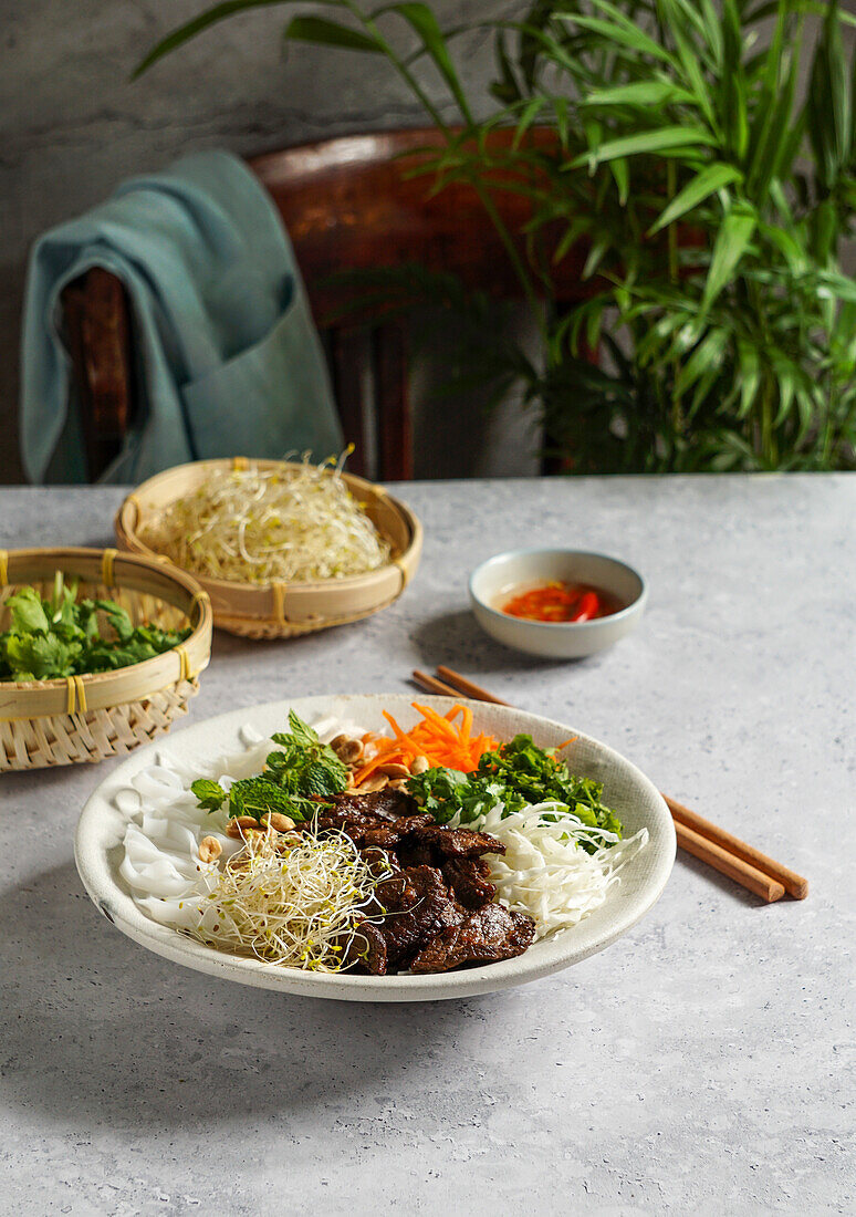 Bun Bo Nam Bo (vietnamesischer Nudelsalat) mit Rindfleisch, Reisnudeln, frischen Kräutern, eingelegtem Gemüse und Fischsauce