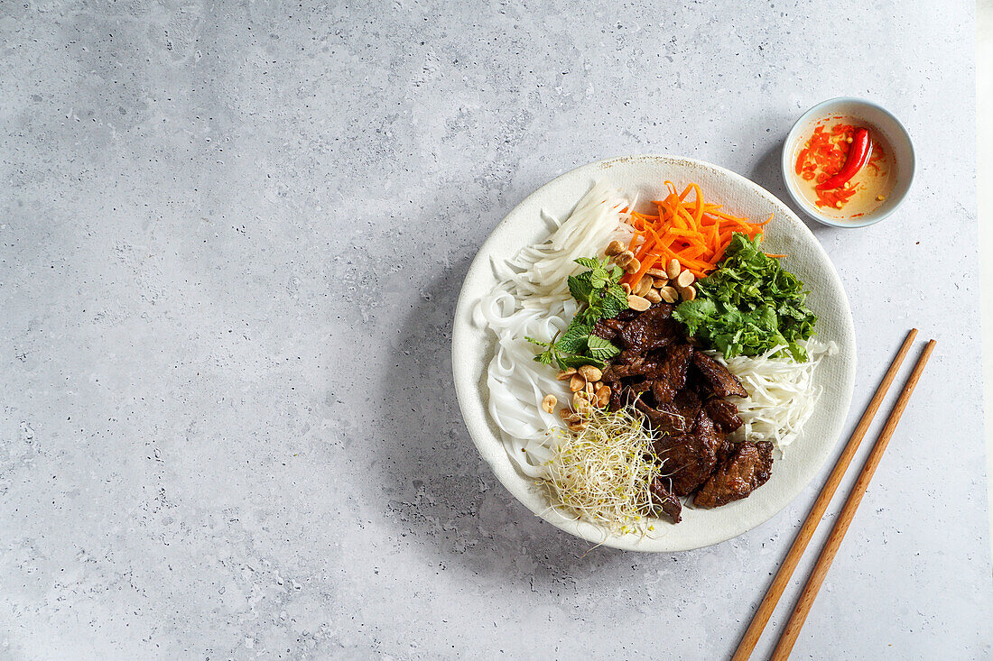 Bun Bo Nam Bo (vietnamesischer Nudelsalat) mit Rindfleisch, Reisnudeln, frischen Kräutern, eingelegtem Gemüse und Fischsauce