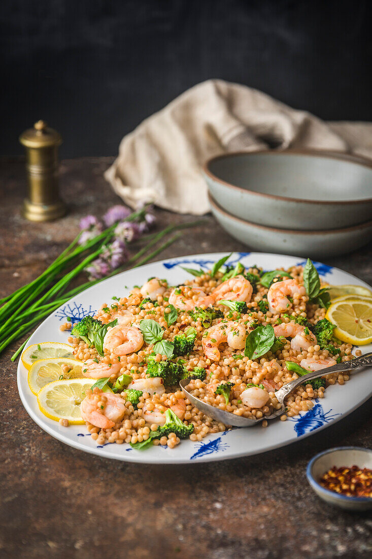 Shrimp with Pearl Couscous and Broccoli on Platter with herbs and serving bowls