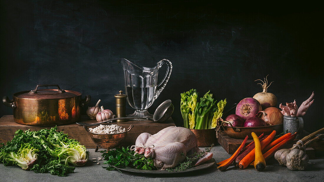 Still life with raw chicken, carrots, chicory with vintage copper pot and crystal jug