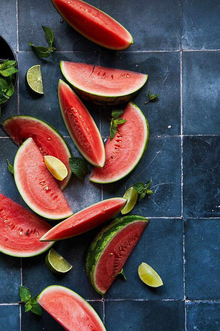 Watermelon wedges with mint and lime on blue tiles