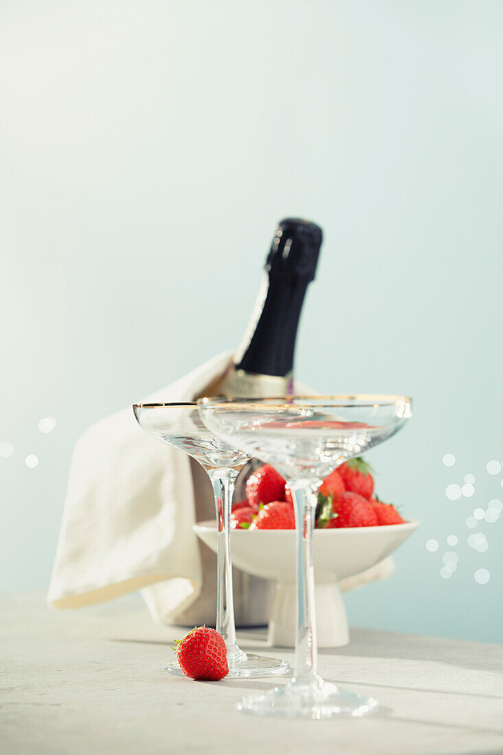 Eine Flasche Champagner, zwei Gläser und Erdbeeren in einer Schale