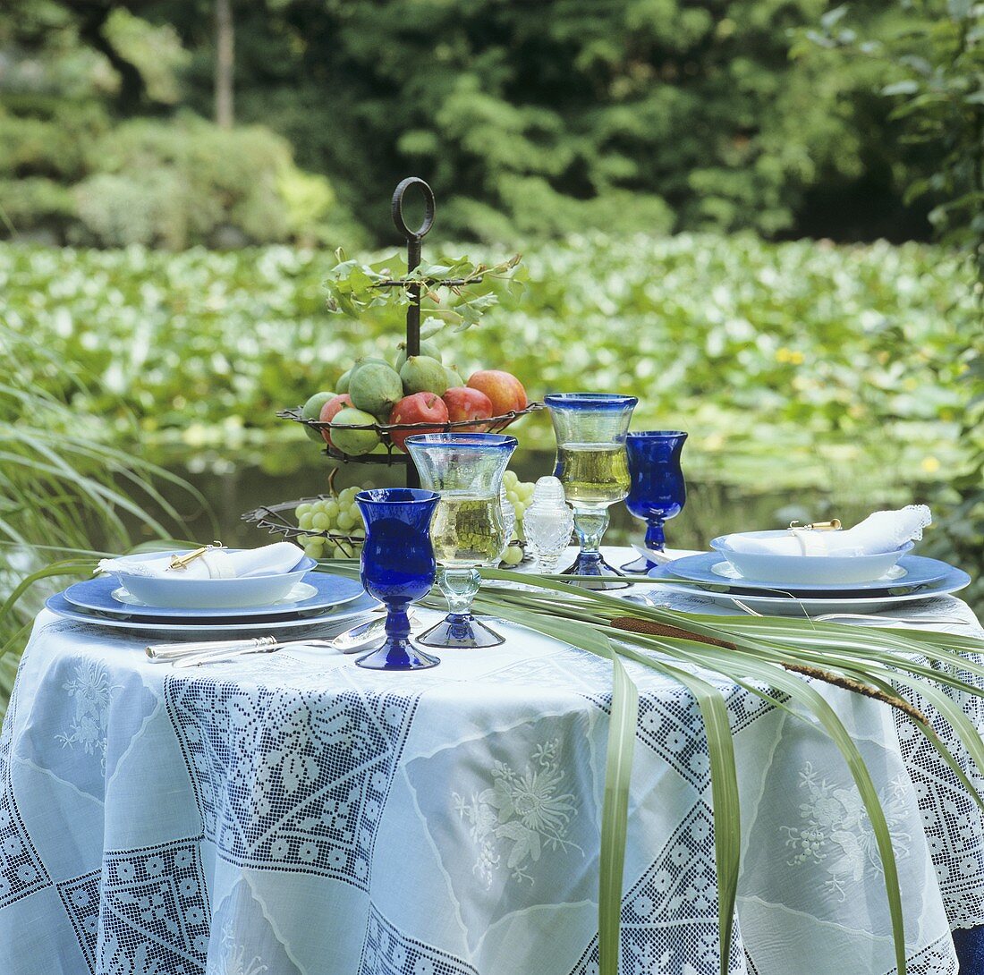 Laid table with tiered stand and lace cover in garden