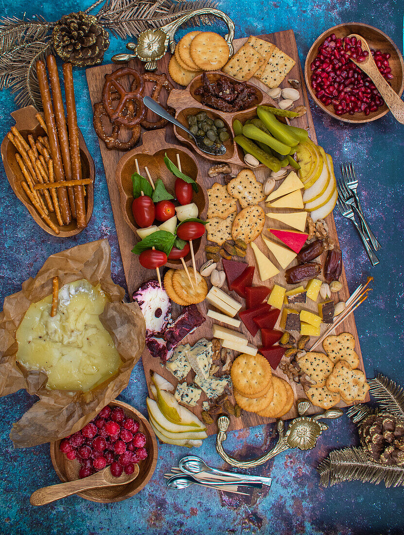 Appetizer board with caprese, cheese, crackers, fruit, and pickles