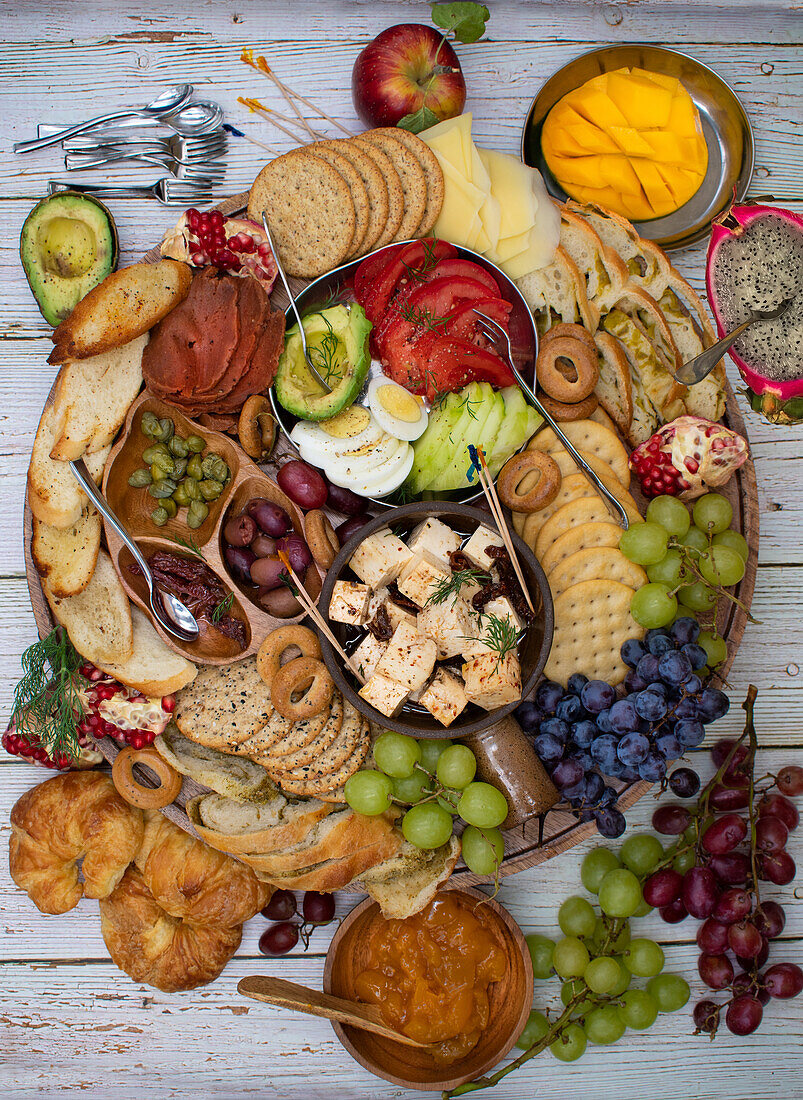 Appetizer board with crackers, cheese, vegetables and grapes