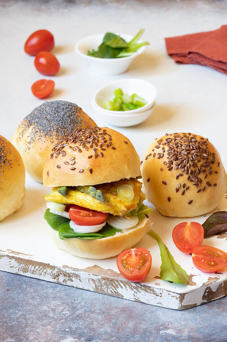 Burger-Buns mit Omelett, Spargel, Frühlingszwiebeln und Tomaten