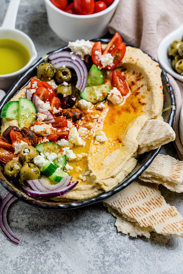 Loaded Hummus-Platte mit Feta, Tomaten, Gurken, Oliven und Zwiebeln
