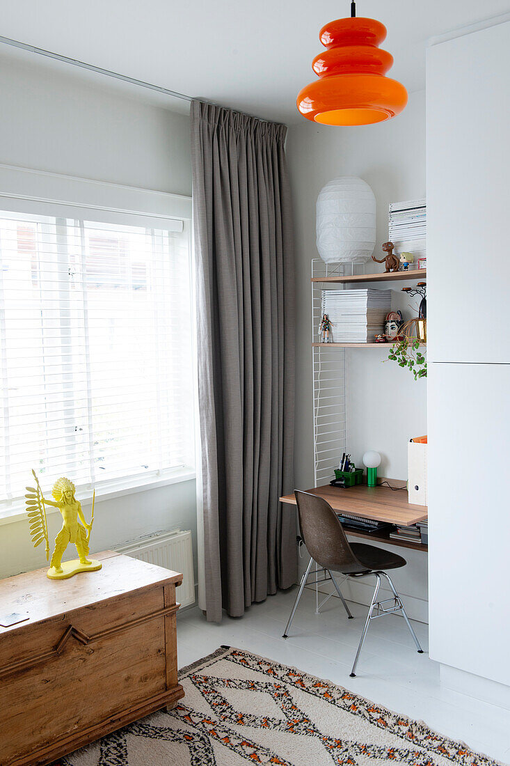 Bright workplace with orange hanging lamp and wooden chest