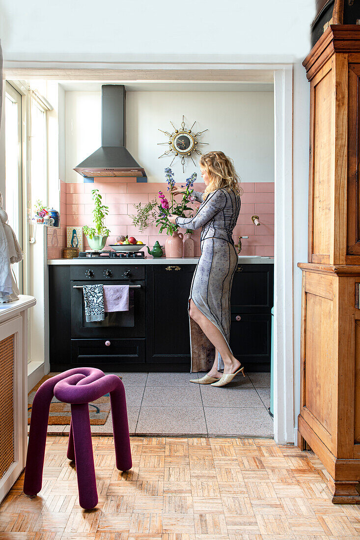 Woman decorates black kitchen unit with fresh flowers in vase