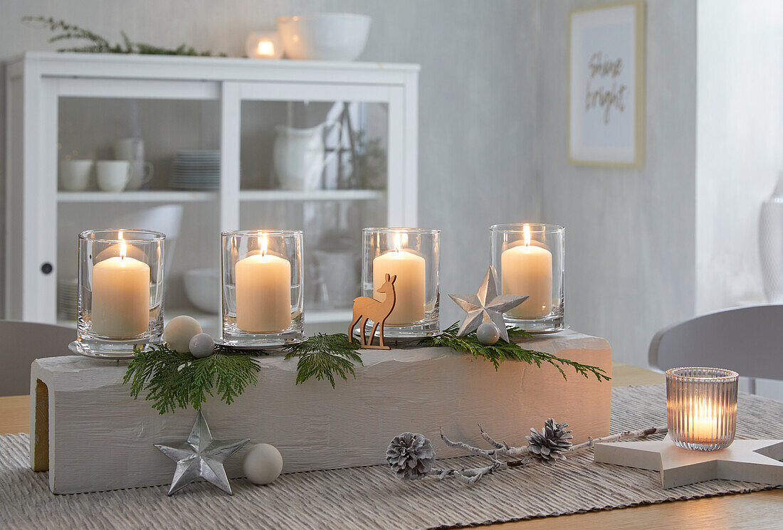 Advent chandelier with candles and fir branches on wooden table in dining room