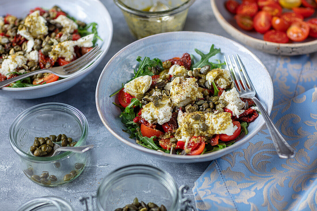 Tomaten-Mozzarella-Salat mit getrockneten Tomaten, Rucola und Kapern