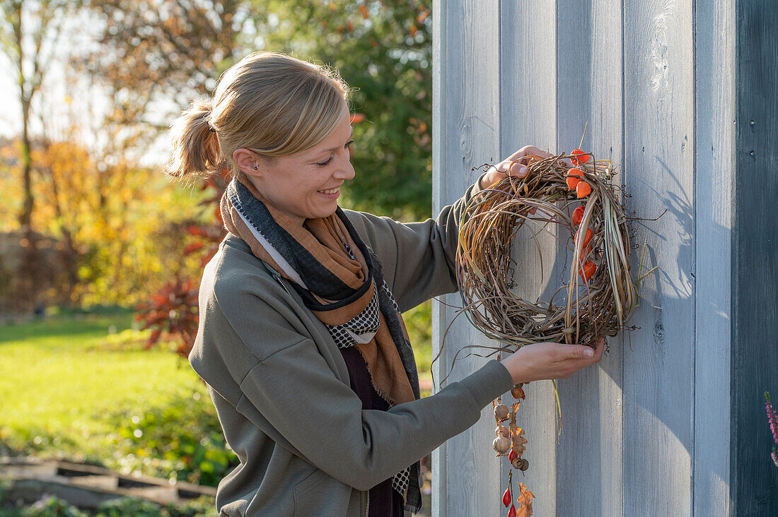 Herbstkranz aus Rückschnitt von Wein und Chinaschilf mit Lampionblumen (Physalis), Mohnkapseln und Hagebutten