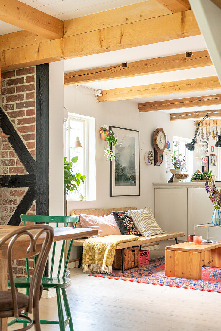 Open-plan cooking, living and dining area in vintage style with wooden beams and brick wall