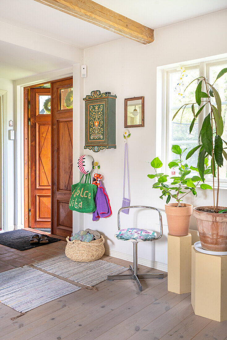 Hallway with wooden door, wall decoration and plants on pillars