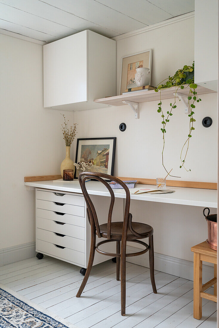 Brightly furnished work area with wall shelf and wooden chair