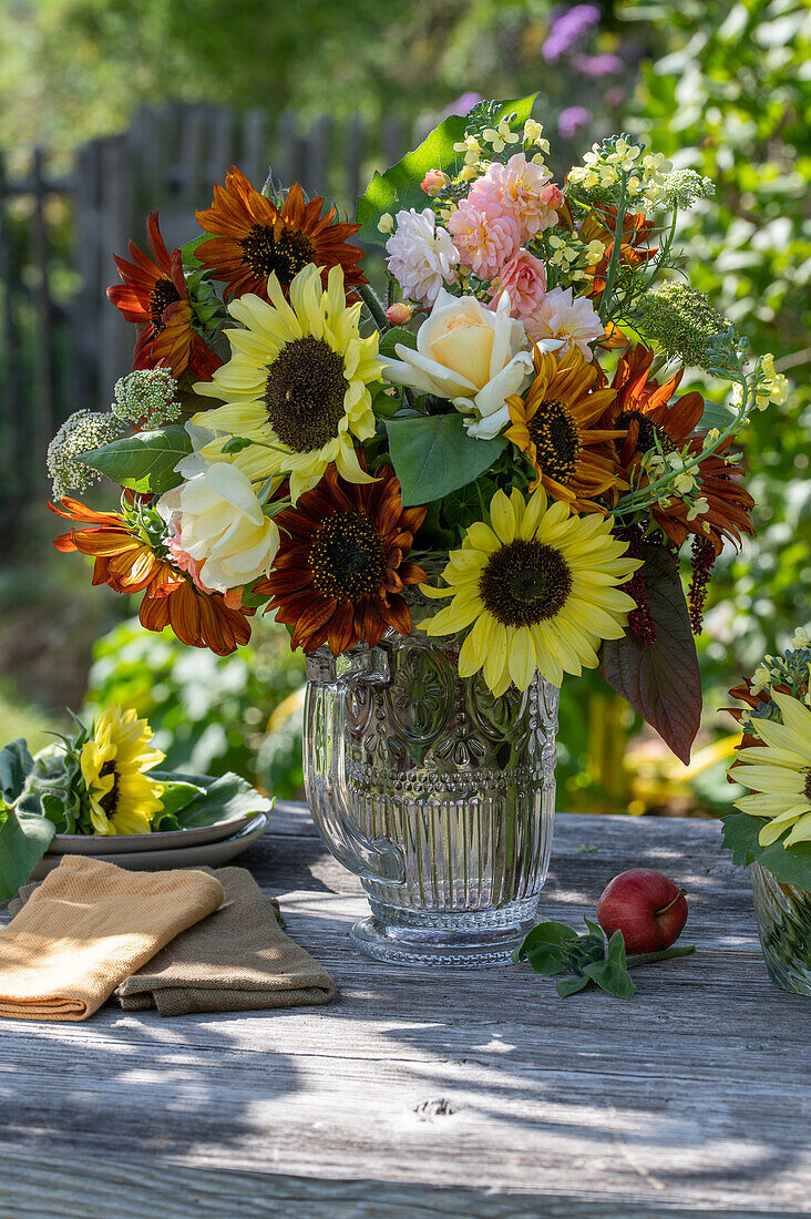 Blumenstrauß mit Sonnenblumen (Helianthus), Rosen (Rosa), Brokkoli, Wilde Möhre, Fuchsschwanz (Amaranthus) auf Gartentisch