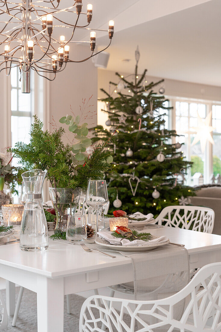 Weihnachtlich gedeckter Esstisch mit Tannenbaum im Hintergrund