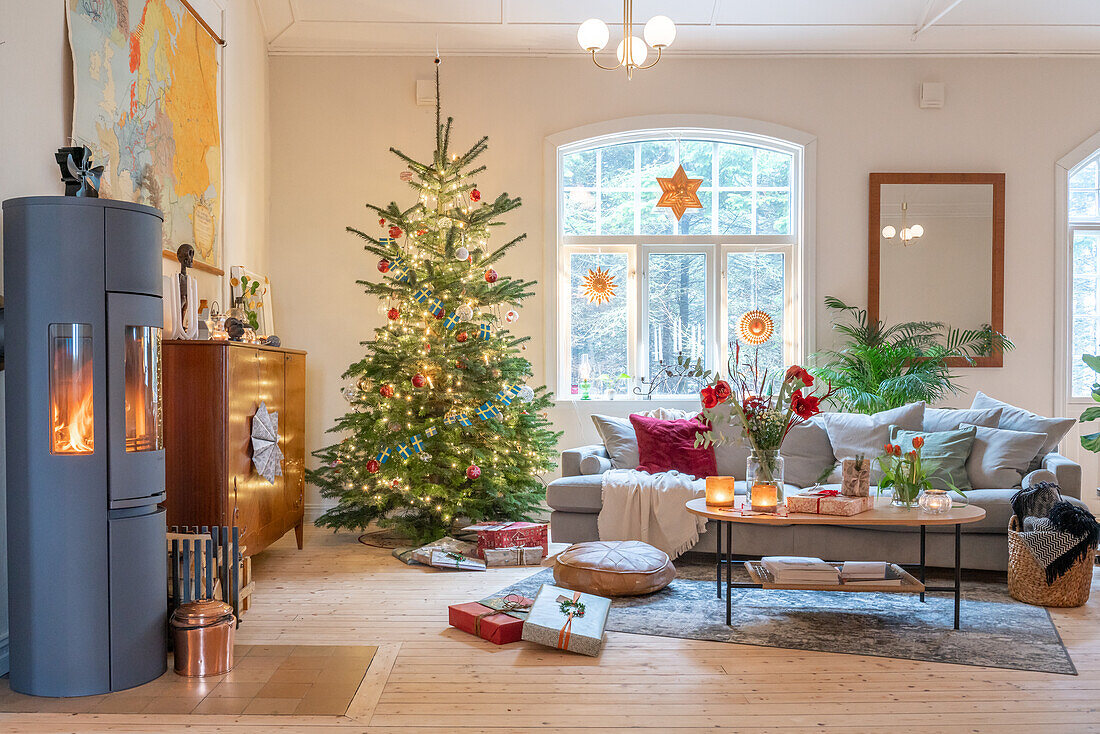 Weihnachtlich geschmücktes Wohnzimmer mit Tannenbaum und Kaminofen