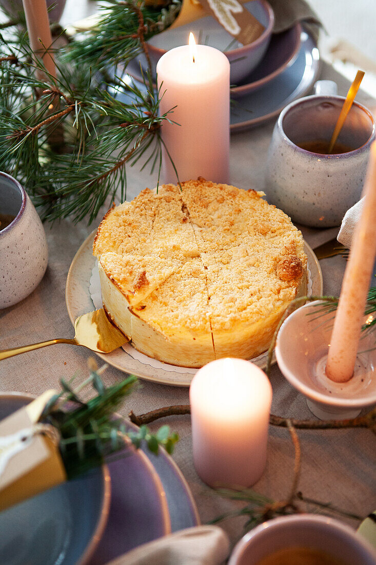 Gedeckter Tisch mit Kuchen und Kerzen, Tannenzweige als Deko