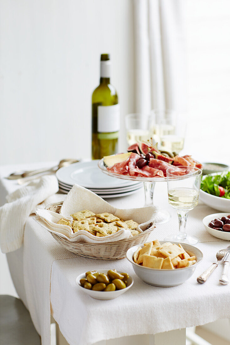 Aufschnittplatte mit Salami und Schinken dazu Oliven, Cracker und Wein