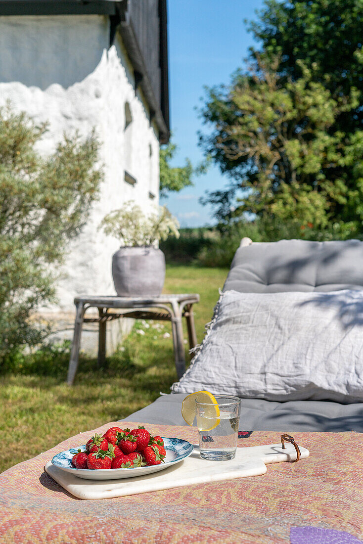 Entspannungsecke im Garten mit Liegestuhl und einem Teller Erdbeeren