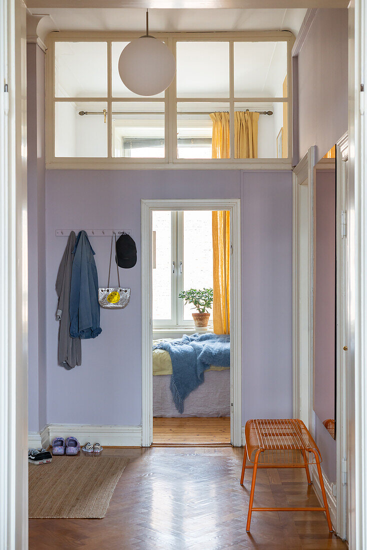 Hallway with purple walls, coat hooks and view of the bedroom