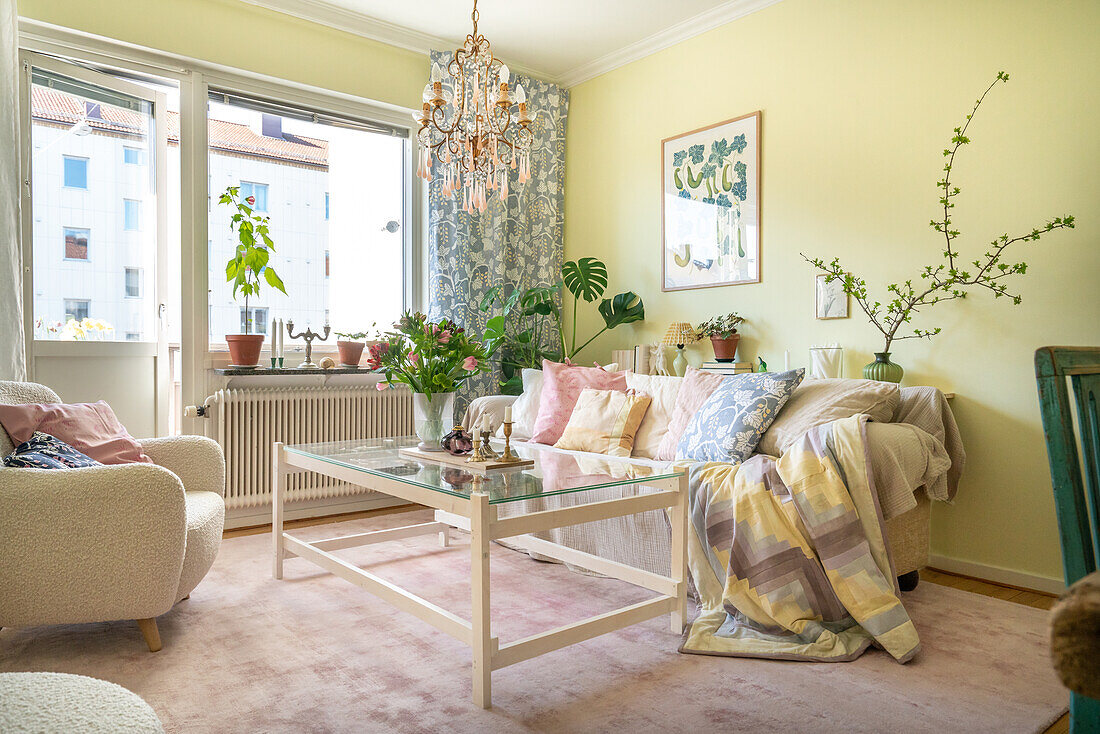 Living room with yellow walls, glass coffee table and crystal chandelier