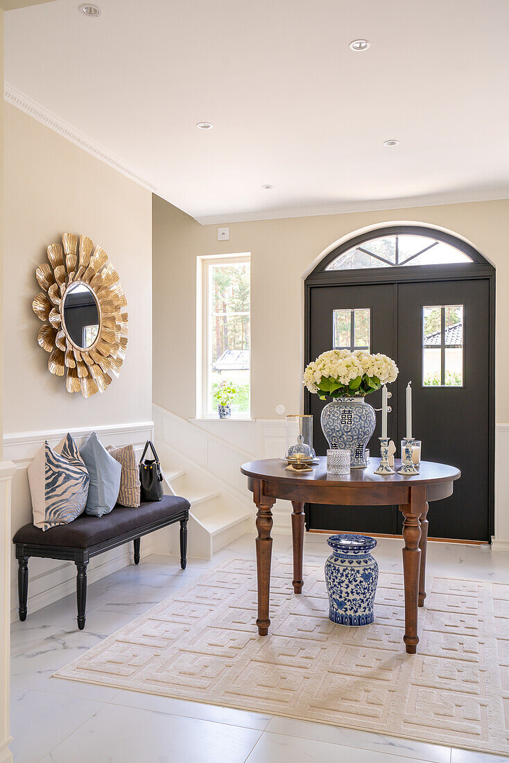 Entrance area with round table, mirror and bench with decorative pillows