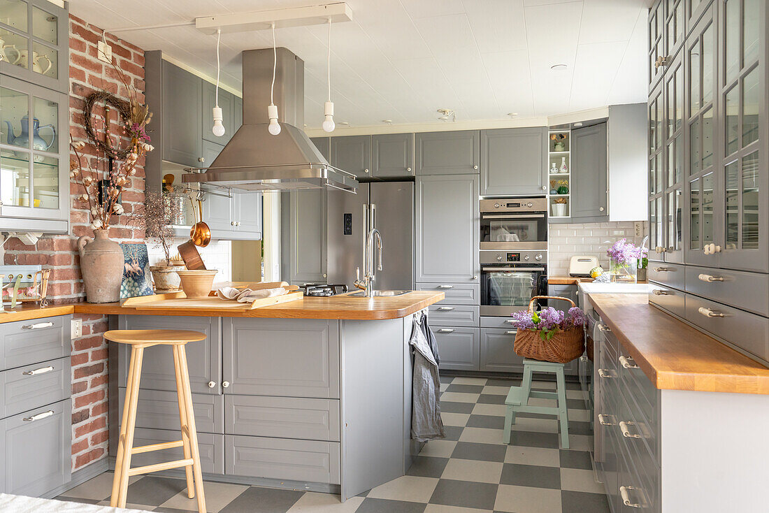 Modern kitchen with kitchen island, brick wall and grey and white checkered floor