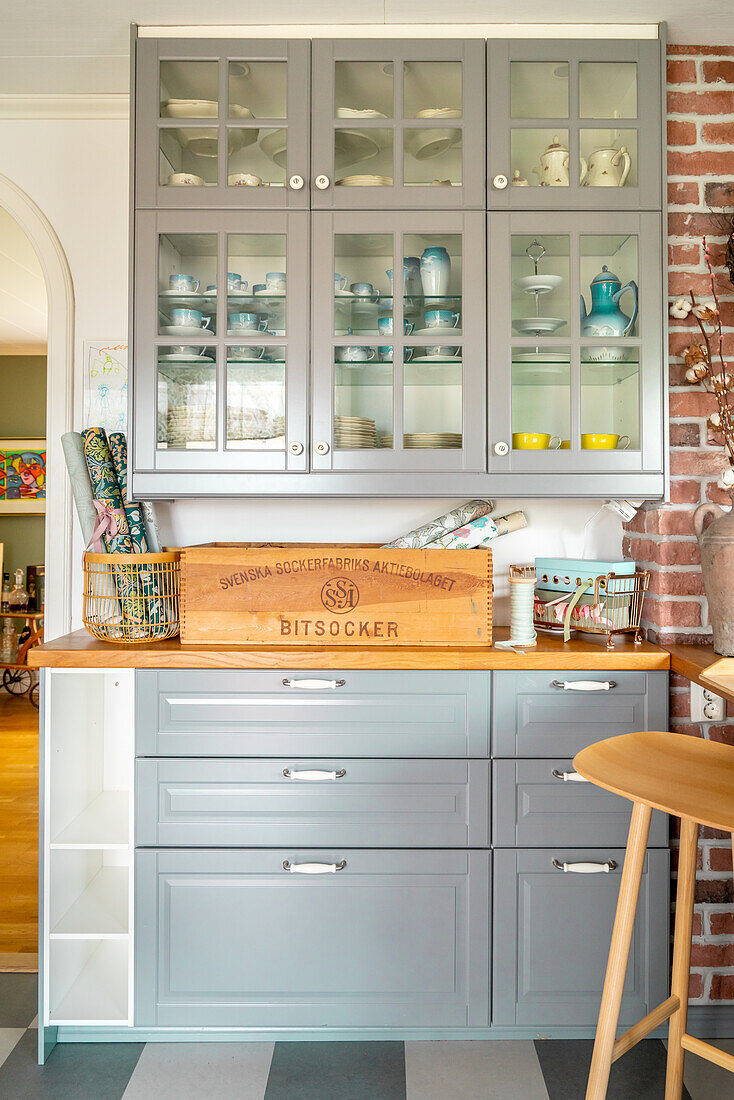 Light grey kitchen with glass doors on the wall units and wooden counters