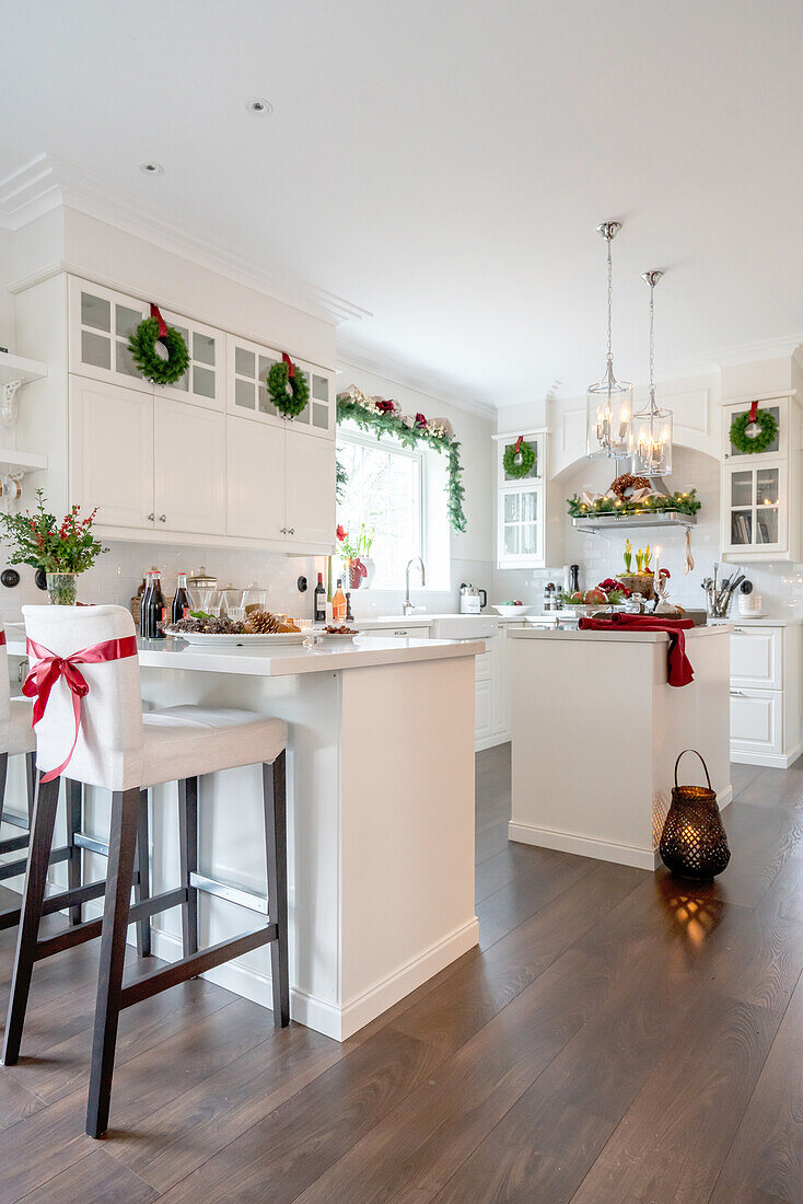 White kitchen with Christmas decorations, counter, bar stools and pendant lights