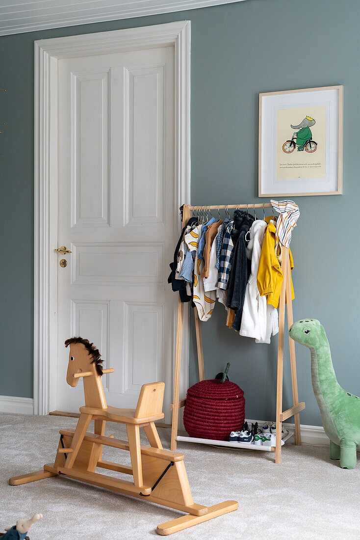 Kinderzimmer mit Holzschaukelpferd, Kleiderständer und Bild